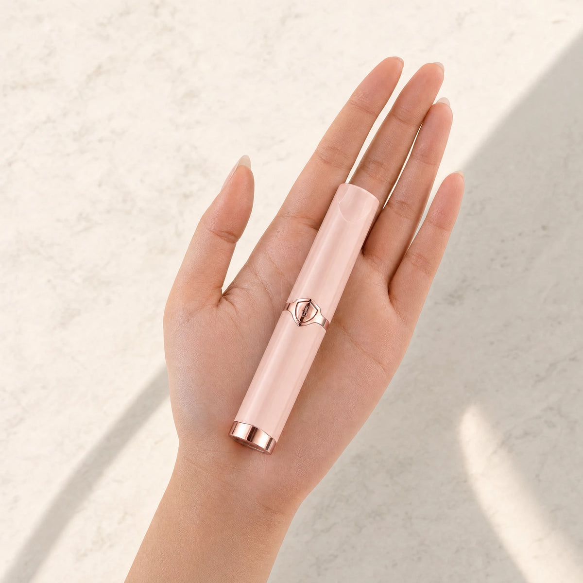 Pink Lumivea heated lash curler resting in a hand